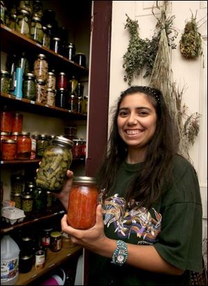 Catherine Hernandez with jars of stewed tomatoes and asparagus from her pantry.