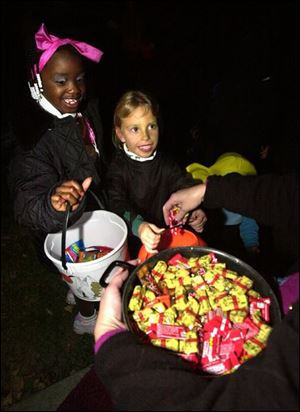 After delivering their opening line of 'trick or treat', Tayla Motley, 6, and Kristen Turner 5, receive candy at a Wallwerth Drive home in West Toledo.