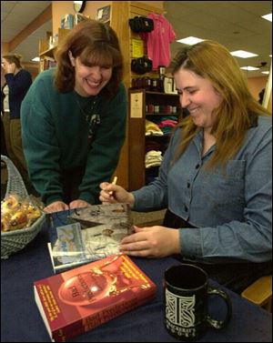 Laura Lee, right, signs a copy of her book, pictured at right, for Jennifer Hunt of Swanton at Thackeray's Books.