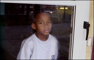 David Pope, 7, peeking out the door of his Prospect Street home, came home Monday from Toledo Children's Hospital. He'd been shot Nov. 18.
