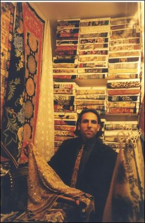 In a tiny cubbyhole of a shop, this vendor shows some of his thousands of silk scarves.
