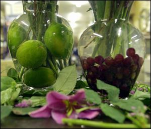Limes and grapes are used as bases in vases of cut flowers.