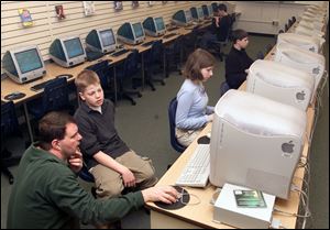 Librarian Walt Connolly helps sixth grader Tyler McMaster get on the Internet at Sylvania's Arbor Hills Junior High while seventh grader Janice Pisello and sixth graders Matt Slattery and Ben Ward work at computers, in background.