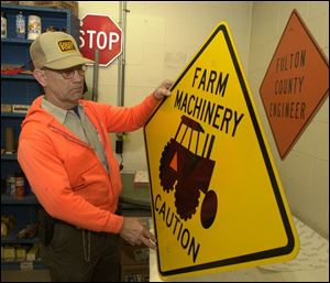Bill Eddings, with one of Fulton County's warning signs that will keep him busy this week, will be replacing signs warning motorists of ice with ones warning of farm machinery.