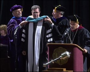 Dr. Thomas Gouttierre is given a BGSU honorary doctor of international relations degree from Dr. John Folkins, left, and Dr. Don Nieman, right, as Dr. Sidney Ribeau, university president, presides.