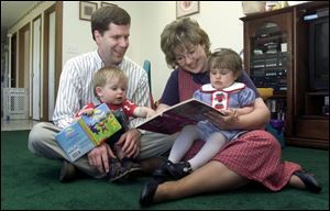Amy and Jim Both read with their children, 26-month-old Katie and 17-month-old Alex, in the living room of their home in Holland.