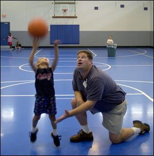 Tim Yenrick, under whose direction the center has expanded greatly, shows Tyler Sarra, 7, how to shoot a basketball.