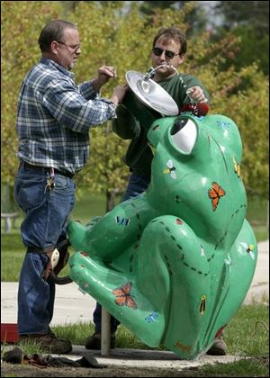 City workers Joe Collins, left, and Chris Dudek make final adjustments to the ‘Got Bugs?' water fountain, the last frog to go in, while installing it in Sleepy Hollow Park.