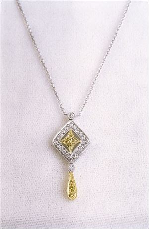 Yellow and white diamonds sparkle in yellow and white-gold settings on this delicate pendant.
