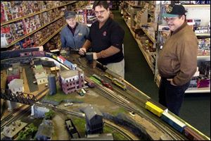 Steve Scanes, center, demonstrates a train at Steve's Hobbies in Sylvania to customers Joe Walczewski, left, and Tom Holmes. Scanes is preparing for the train show on Sunday.