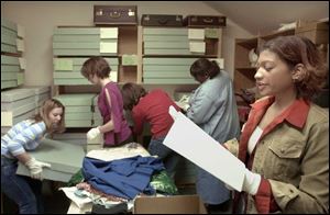 Bluffton College students Tanisha Seibert, Janet Rebekah Moyer, Rebekah Wingert, and Sonya Phillips, from left, try to find Mennonite clothing that Amanda Mills, right, requested from archival boxes in the storage room.