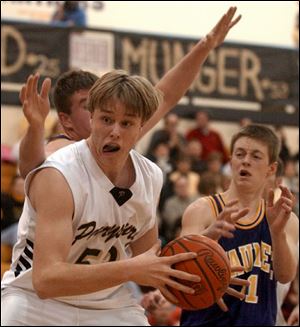 Perrysburg's Hal Munger (53) drives through Maumee defenders last night at Perrysburg. Munger and Mike Mefferd led the Yellow Jackets with 10 points apiece. Munger also grabbed seven rebounds and blocked four shots.