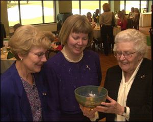 Toledo Area Delta Gamma Alumnae Group Chapter co-presidents Carol Robinson, left and Cindy Hoffman, center, look over a glass bowl with Merle Blank, who was recognized as a 65-year member of the group during the brunch at Inverness Club.