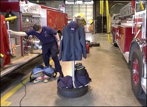 Firefighter Sgt. Dennis Peters removes his gear after a run from the central fire station.