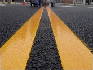 ROV May 6, 2002 - Mike Cuevas, left, and Lorraine Zimmerman of Zimmerman paint Co., Fremont, O., apply new lines on Washington St. near Superior Street in downtown Toledo Monday morning.  The material they put down is not paint but plastic which outlasts paint.   Blade photo by Dave Zapotosky