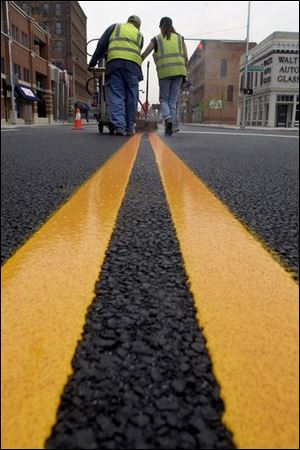 ROV May 6, 2002 - Mike Cuevas, left, and Lorraine Zimmerman of Zimmerman paint Co., Fremont, O., apply new lines on Washington St. near Superior Street in downtown Toledo Monday morning.  The material they put down is not paint but plastic which outlasts paint.   Blade photo by Dave Zapotosky