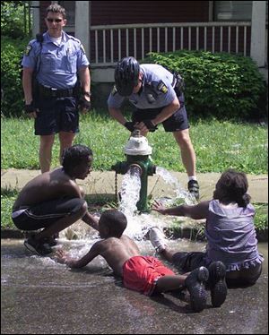 Officer Greg Mahlman watches Tysean Haynes, 13, Regan Williams, 10, and Candance Haynes, 12, from left, enjoy a final splash from a hydrant on Cumberland Street as his partner, Officer Bill Michalski, turns off the water.