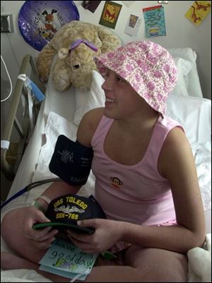 Alyssa Reed, 12, at Toledo Children's Hospital, receives a hat and Mud Hens tickets from the sailors of the USS Toledo.