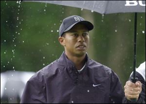 Tiger Woods keeps temporarily dry under an umbrella held by caddie Steve Williams on the eighth tee at the Bethpage Black course in Farmingdale, N.Y.