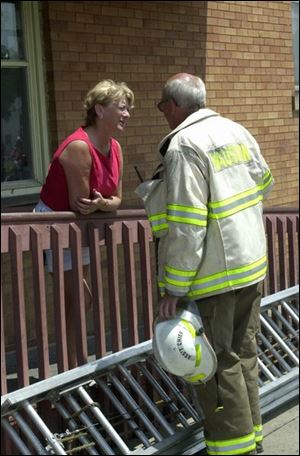 Barbara Galvin talks with Assistant Fire Chief Fred Allen. A blaze Friday ruined a nearby building and damaged her shop.