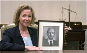 Marsha Manahan, new Toledo Bar Association president, holds a portrait of her father, Thomas Manahan, a past president of the group.