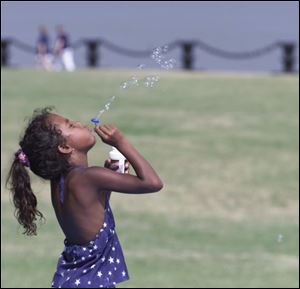 Toledoan Tia Howe, 7, blows bubbles in Promenade Park while waiting for the fireworks.