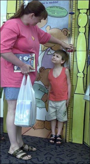 Caryn Meyer measures her son, Jeffy, 5, at one of the exhibits inside the Toledo-Lucas County's Main Library.