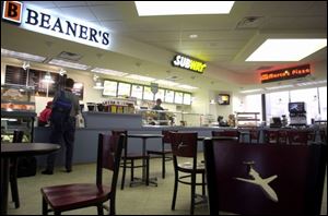 An airport patron stops for a cup of coffee at the new, 1,800-square-foot area on the terminal's second floor, which features an L-shaped food counter offering Marco's Pizza, Subway, Beaner's coffee, Toft's ice cream, and T.J. Cinnamon's baked goods on one side, a relocated bar on the other, and tables in between.