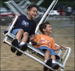 Gary Wend, 7, left, and his brother Grant, 4, are all smiles as they whirl around in circles on the Trooper, one of the carnival rides at the Pemberville Fair.