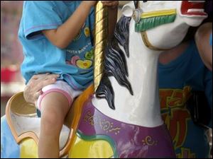 REG fair16p 081602 B August 16, 2002-- Riding the Merry-Go-Round wasn't as fun as it looked for Mamie Opal Hughes, 5. The Lima youngster made it around once before demanding to get off the ride at the Allen County Fair in Lima Friday. Her mother Delores Sowders did convince her to try sitting in the carriage though and that seemed to do the trick as she was all smiles the rest of the way. Blade photo by Andy Morrison