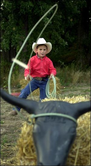 ROPE 'EM, COWBOY: Clay Vaughan, 6, lassoes his steer.