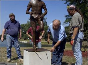 CTY sculpt30p 083002  August 30 2002--From left, Ken Thompson, Mike Barker, Thomas Lingeman and Alan Knaggs level a sculpture of legendary UT marathoner Sy Mah after installing it at Olander Park in Sylvania. It took Lingeman 18 months to create the 240 pound bronze sculpture which they installed Friday afternoon. Blade photo by Andy Morrison