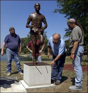 CTY sculpt30p 083002  August 30 2002--From left, Ken Thompson, Mike Barker, Thomas Lingeman and Alan Knaggs level a sculpture of legendary UT marathoner Sy Mah after installing it at Olander Park in Sylvania. It took Lingeman 18 months to create the 240 pound bronze sculpture which they installed Friday afternoon. Blade photo by Andy Morrison