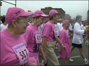 Local cancer survivors Jeanne Aust, Helen Roberts, Jennie McAdams, and Mary Chris Skeldon, from left, make their way up Summit Street in downtown Toledo during the ninth annual Race for the Cure.