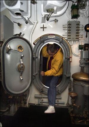Toby Oothoudt demonstrates what a tight fit the hatches are on the World War II submarine USS Cod.