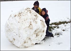 Donald Christon, 12, left, and Derrick Green have trouble pushing a snow ball they spent an hour creating at their Arlington Avenue homes on a welcome day off from school.