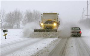 A plow pushes snow off the road and onto a passing car on State Rt. 51 east of Genoa.