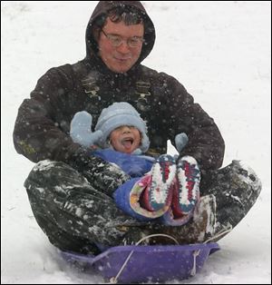 Four-year-old Kasey Hoffman enjoys a wild ride through the snowflakes with her father, Mike, on a hill at Waite High School in East Toledo. The National Weather Service said 4 inches of snow fell on the area yesterday, which was a lot of fun if you weren't trying to drive in it.