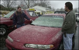 Keir Schlatter examines a car at A&S Auto Sales, where owner Norm Maran, right, says values have increased.