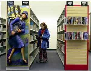 Ciera Wilkinson, 10, of Sylvania looks over the book selection at the Toledo-Lucas County Public Library downtown.