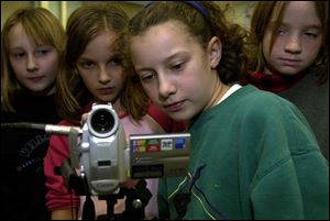 Abigail Jacoby, from left, Hayley Hutchinson, Veronica Zimmerman, and Danielle Smith, all 9, check the back of the camera for audio for their TV show.
