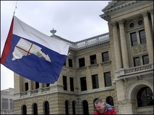 ROV February 4, 2003 - Tom Gerken walks under wind-whipped Lucas County and United States flags flying at half staff on the grounds of the Lucas County Courthouse. The flags are at half staff in honor of the deceased crew of the Space Shuttle Columbia.  Gerken was downtown for jury duty.  Blade photo by Dave Zapotosky
