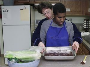 Lori Board shows Rogers High student Seritta Parker how to smooth out a cake mix.