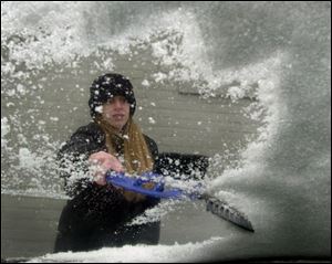 Jill Holbrook of Toledo clears the snow and ice that had accumulated on her windshield while she was parked only a short time on Michigan Street.