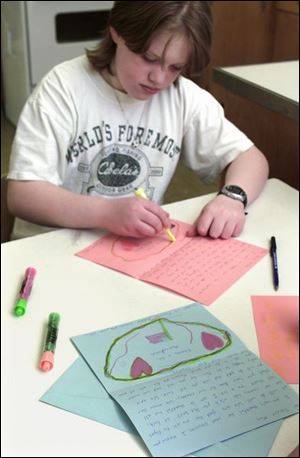 Fassett Middle School sixth grader Monica Reeves writes a letter for her care package.
