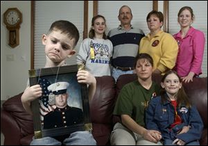 While Marine reservist Cpl. Lance Kokensparger, in portrait, is fighting Iraq, his son, in foreground, Max, 3; wife, Barb, and daughter, Hali, 8, along with his sister, Jennette, 13; father, Larry; mother, Kathy, and sister, Jessica, 16, offer support at home.