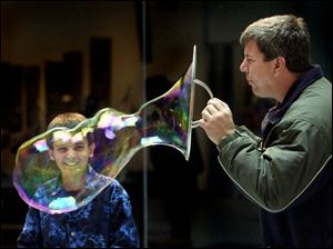Mekkel Richards, 11, is all smiles as he watches Tom Sklar blow an oversized bubble at COSI-Toledo. The two were among a group of Brooklyn Elementary pupils, staff, and parents on a field trip to the science museum yesterday.
