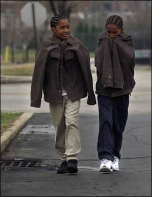 Levell Lane, 10, left, and his brother, Louis, 6, bundle against the cold on their walk home from the Paul Laurance Dunbar Academy. A warming trend beginning today will boost temperatures at least through Sunday.
