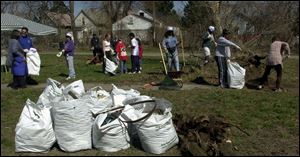 City officials help 40 volunteers fill garbage bags with rubbish and debris from long-abandoned Bronson Park, located between Central and Bronson avenues in North Toledo.