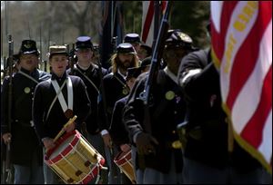 A Civil War re-enactment group representing the 4th Michigan Infantry Regiment stands at attention during the ceremony at Madison and Williams streets in Adrian.